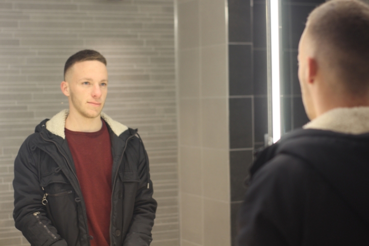 鏡に映る自分を見る男